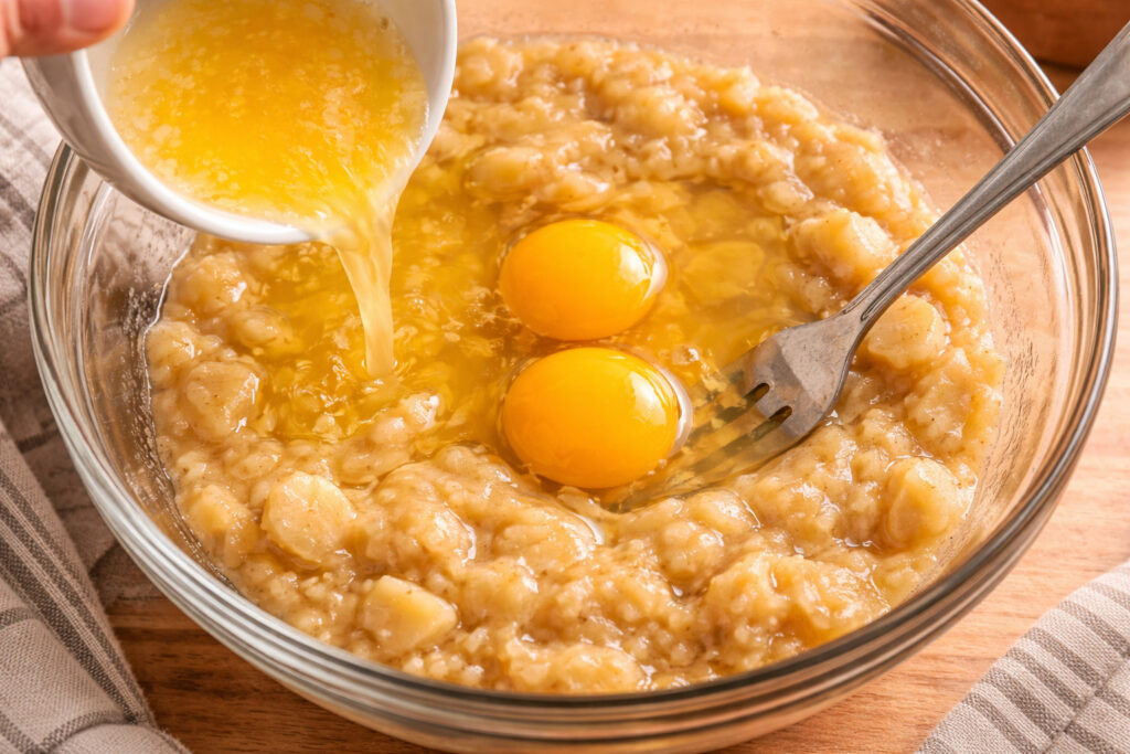 Bananes écrasées à la fourchette dans un saladier avec beurre fondu pour la pâte du banana bread