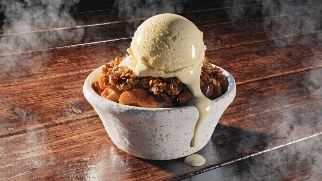 Crumble aux pommes chaud sorti du four avec une boule de crème glacée à la vanille qui fond dessus