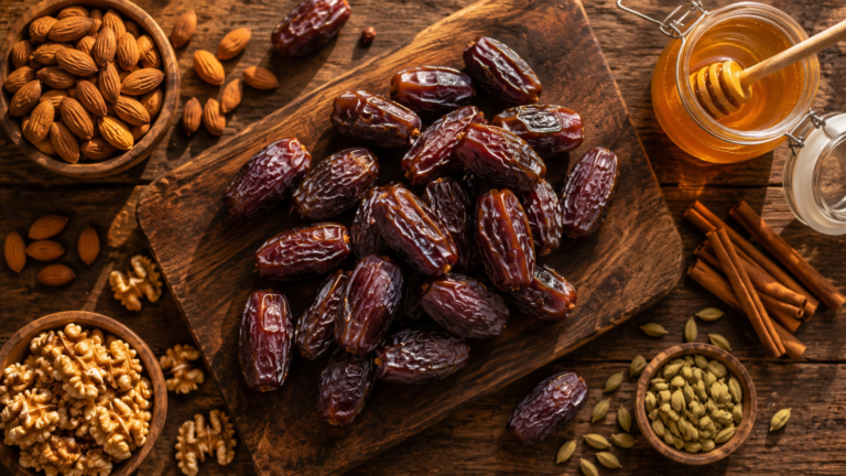 Recettes à base de dattes : dattes Medjool, amandes, miel brut et épices sur une planche en bois